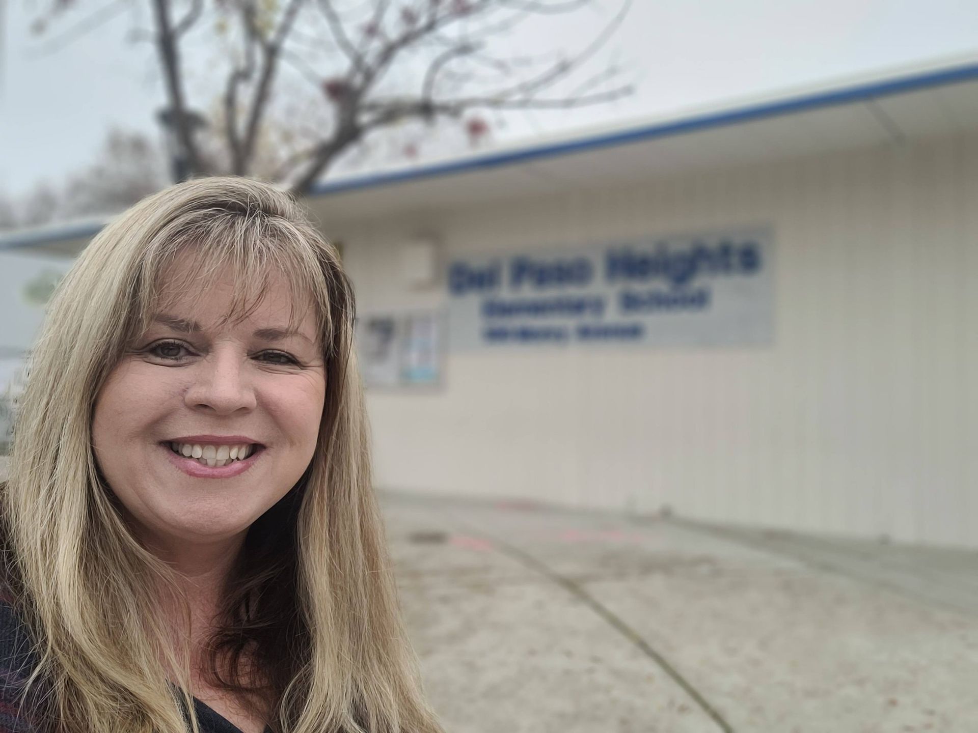 Four women smiling, posing for a photo. American flag in the background. Evening setting.