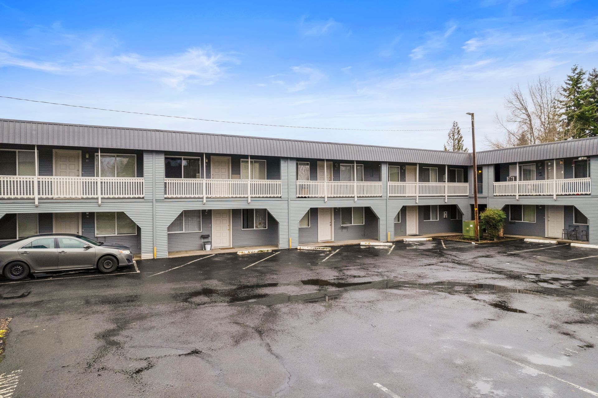 A car is parked in front of a motel building.