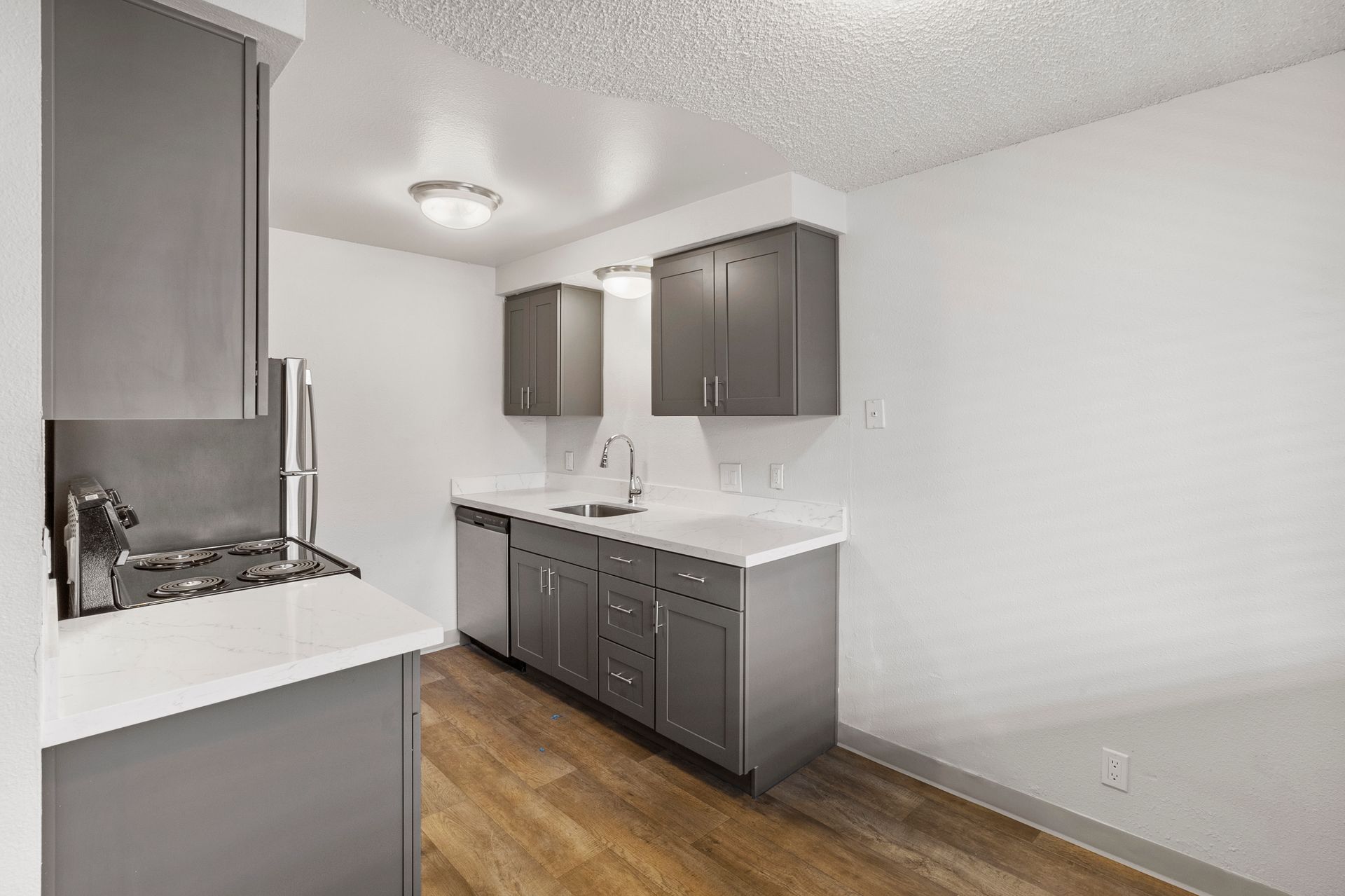 A kitchen with gray cabinets and wooden floors