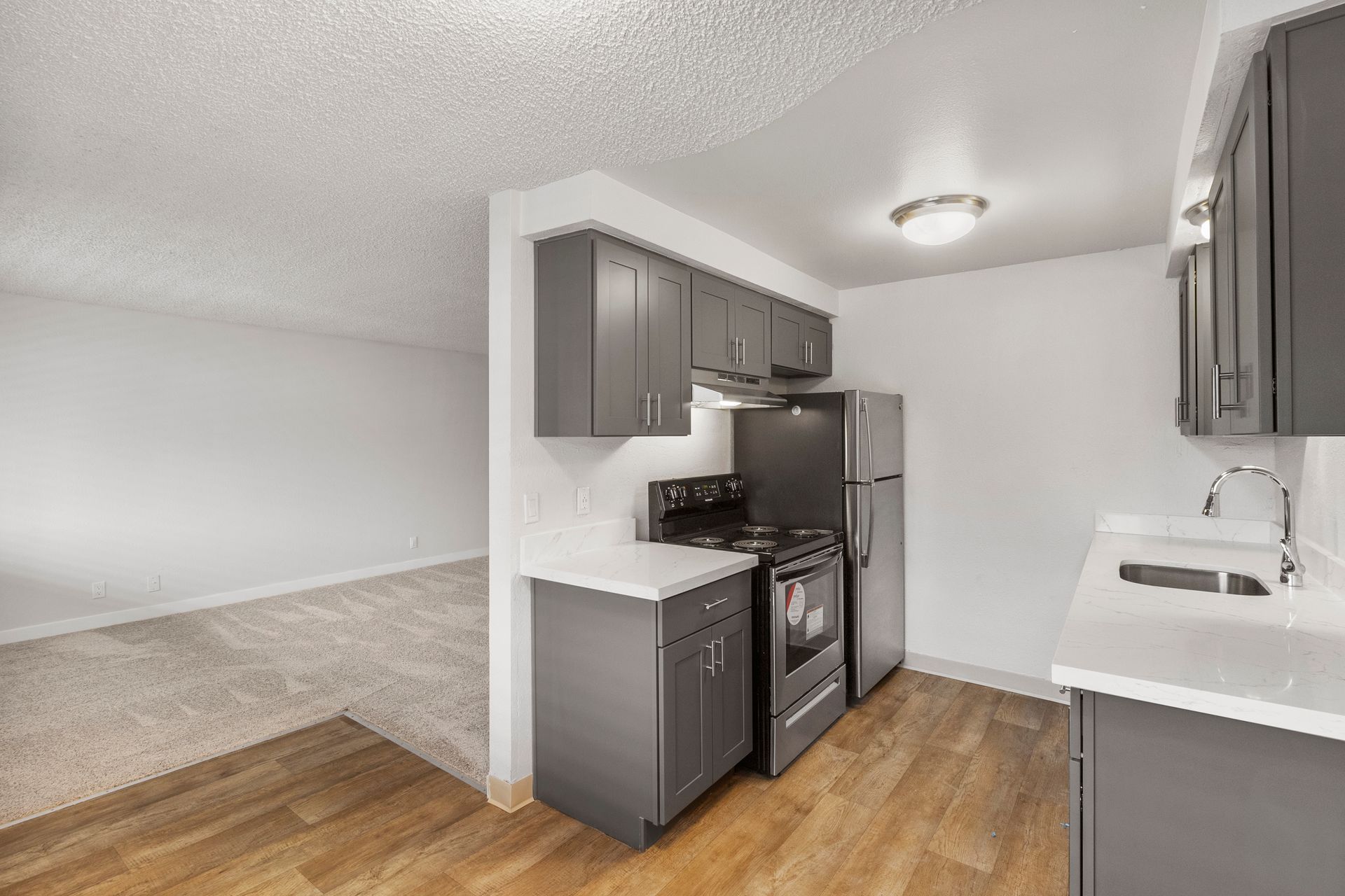 A kitchen with a stove , refrigerator , sink and cabinets.