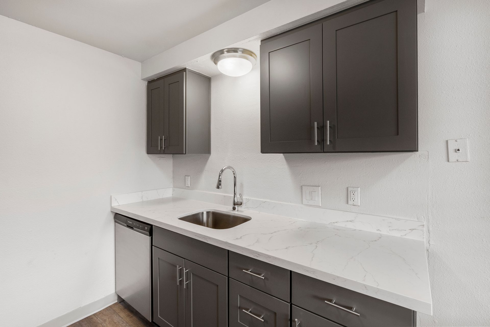 A kitchen with gray cabinets , a sink , and a dishwasher.