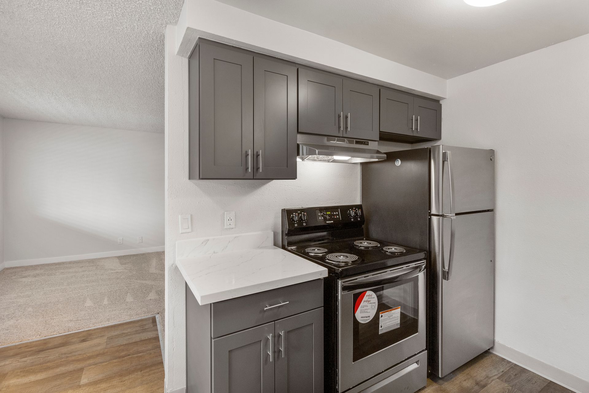 A kitchen with a stove , refrigerator , and cabinets.