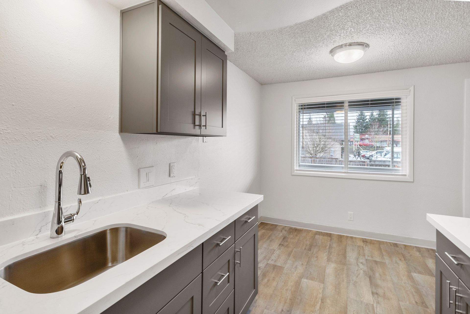 A kitchen with a sink , cabinets , and a window.