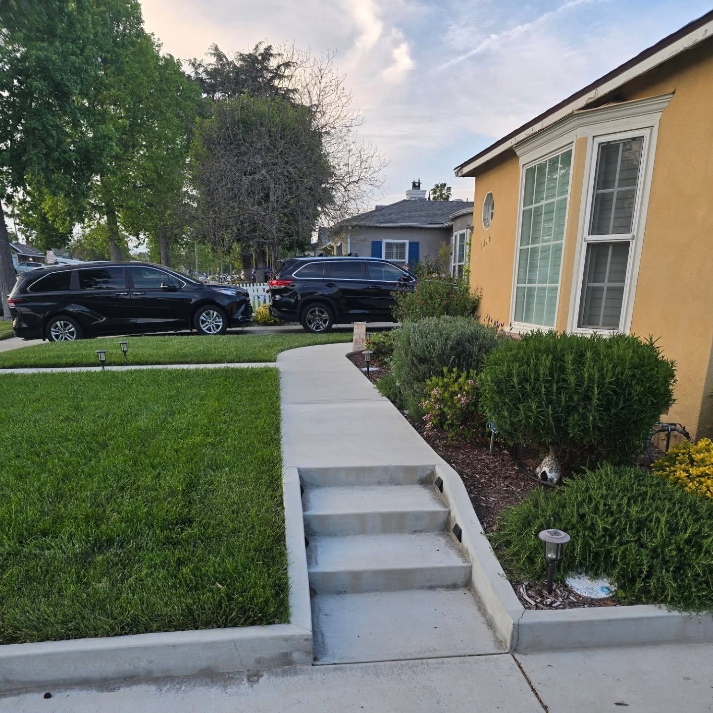 A house with yellow siding, concrete pathway, and steps leading to the front door.