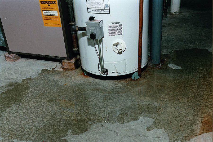 A white water heater is sitting on a concrete floor