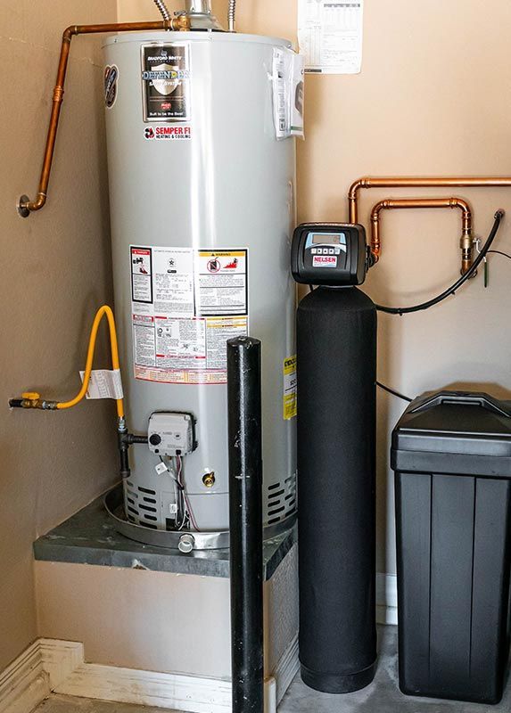 A water heater is sitting next to a water softener in a phoenix garage