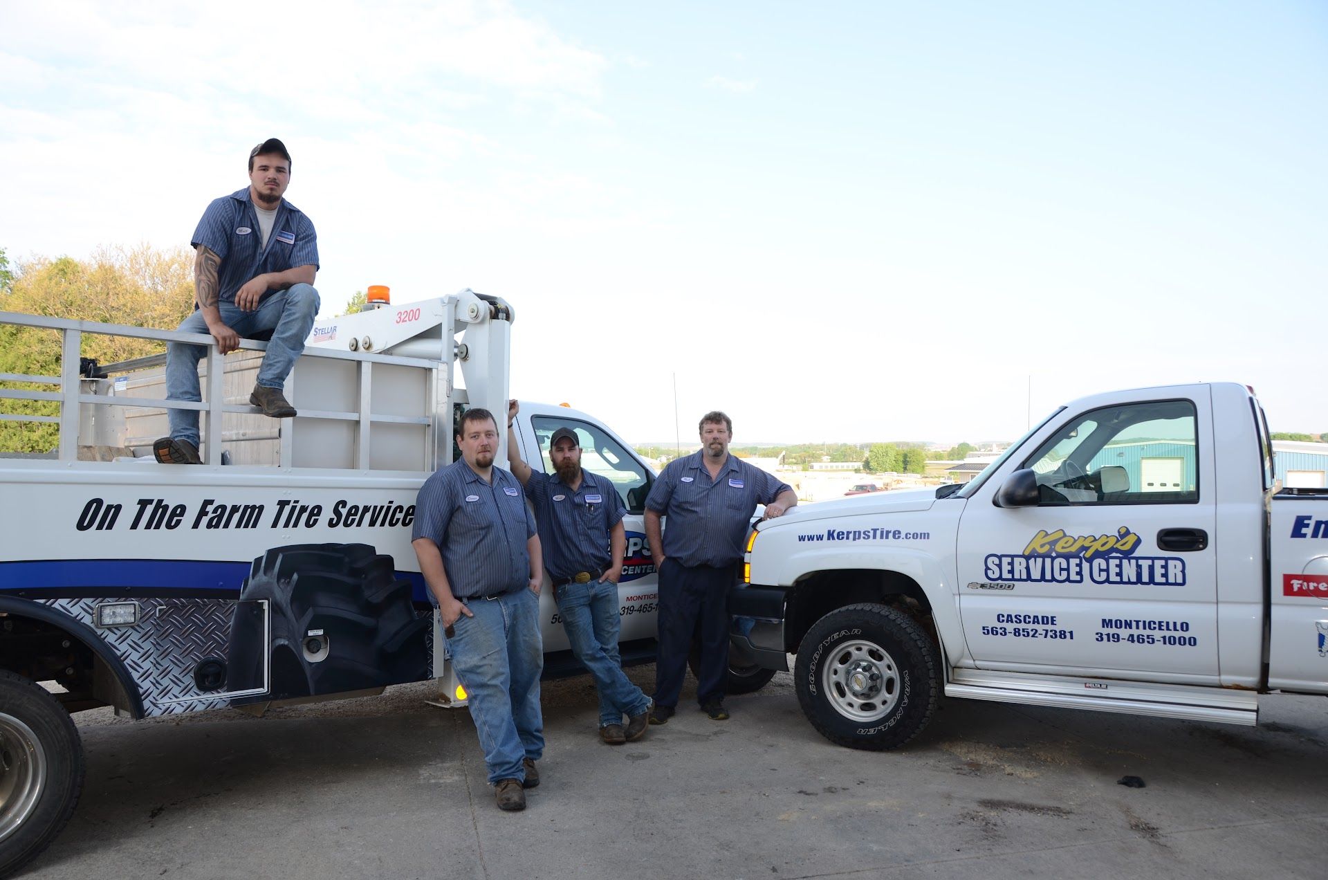 Four men stand near two service trucks. One sits on truck. Trucks are white, with logos | Kerp's Service Center