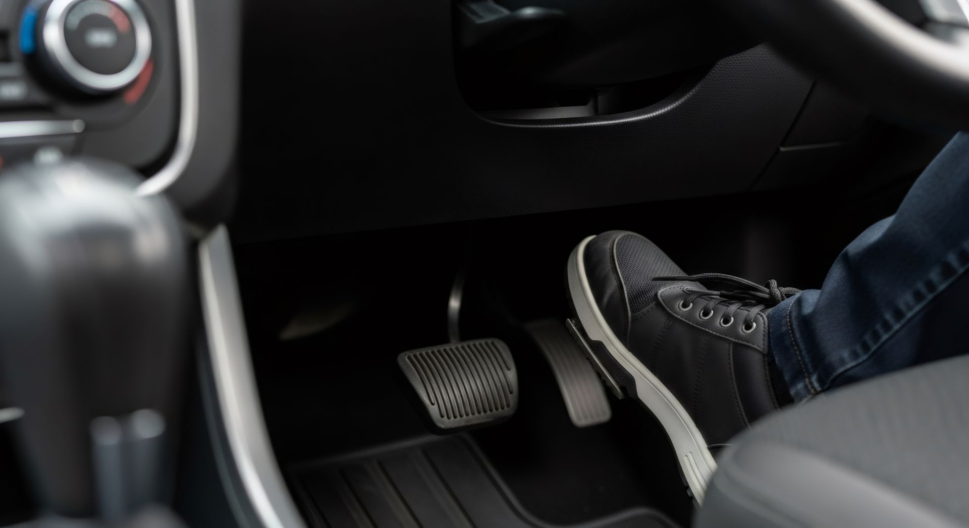 Foot pressing the accelerator pedal in a car.