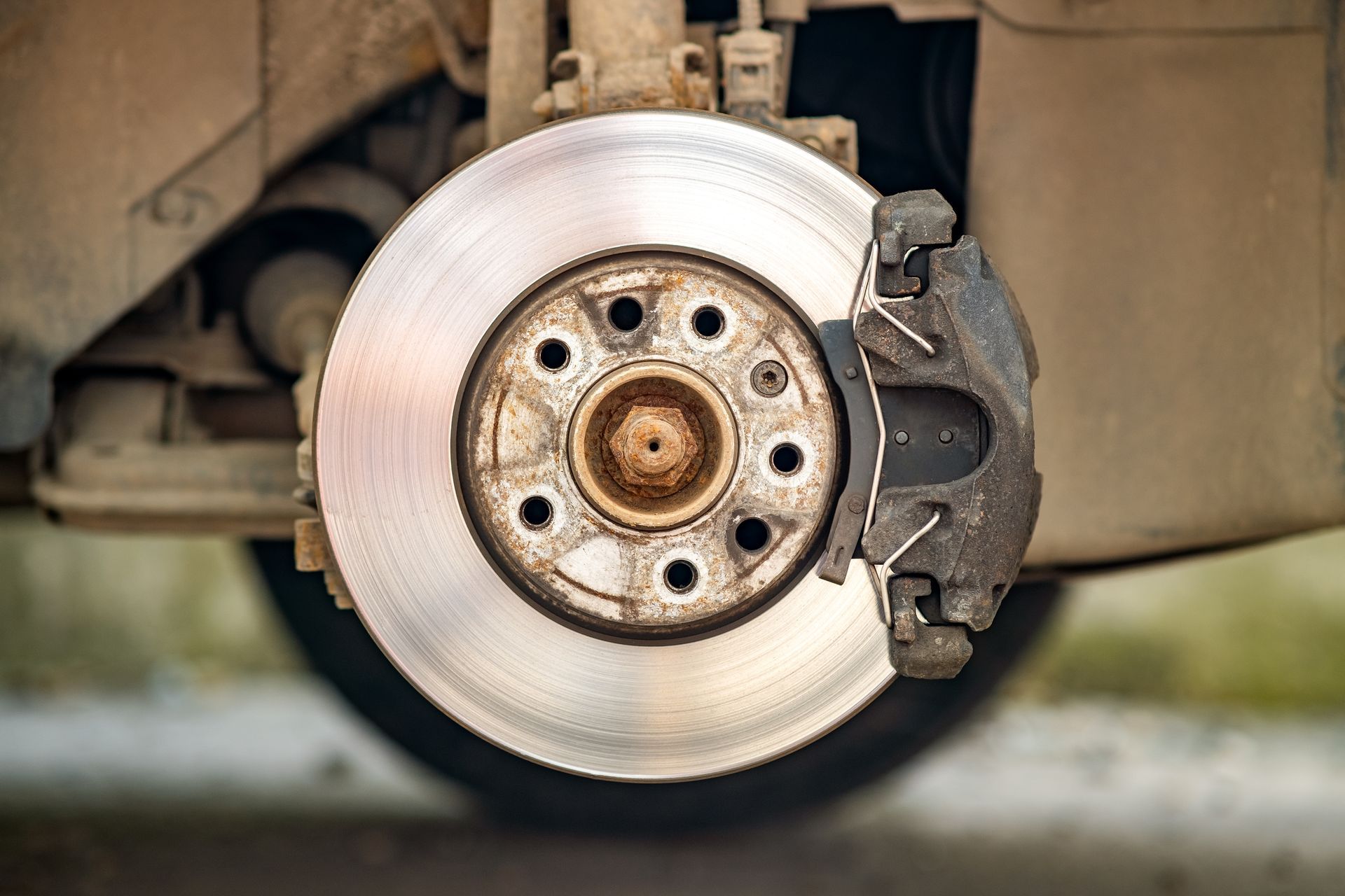 Close-up of a car's brake rotor and caliper, showing wear and tear.