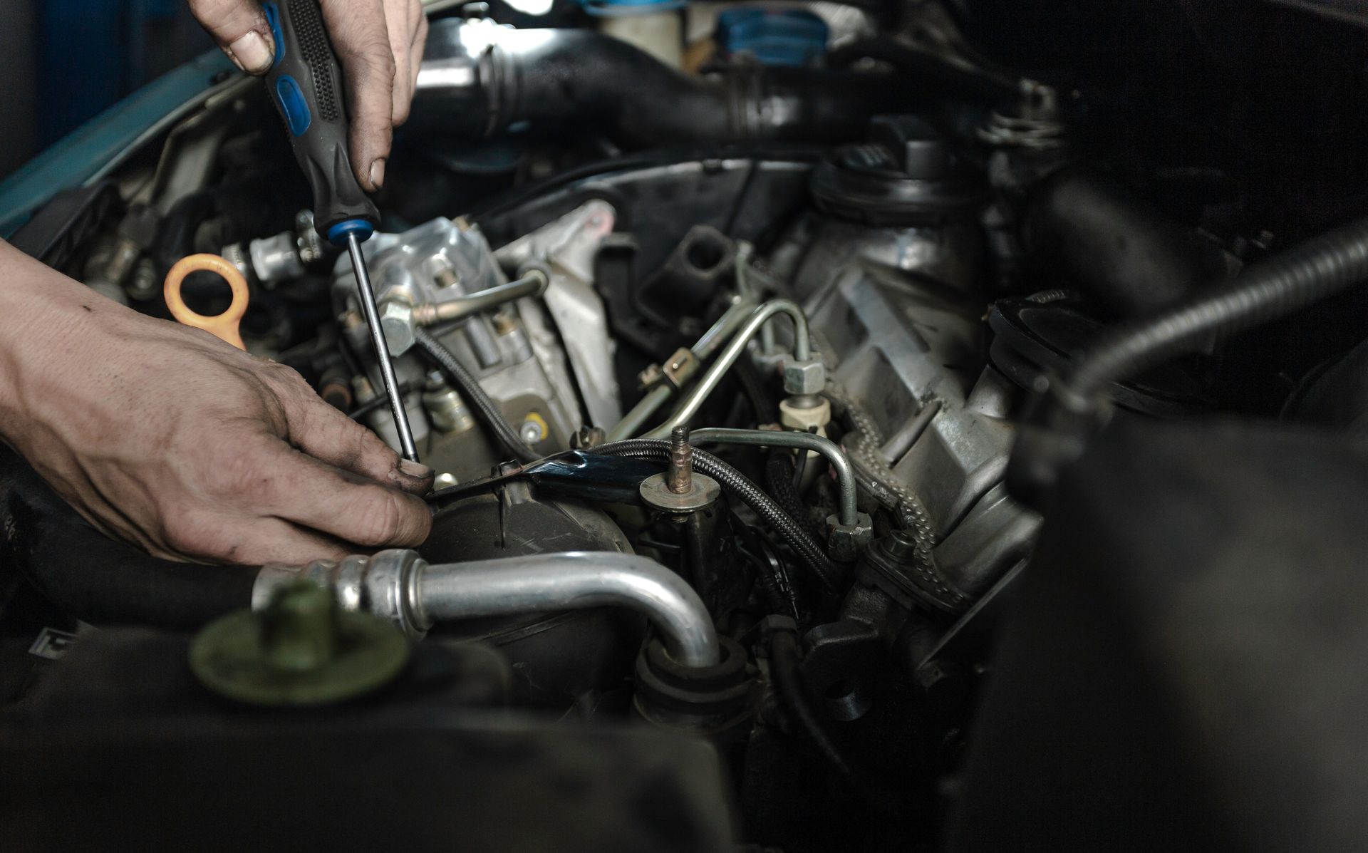 Person working on a car engine with a screwdriver. Person working on a car engine with a screwdriver.