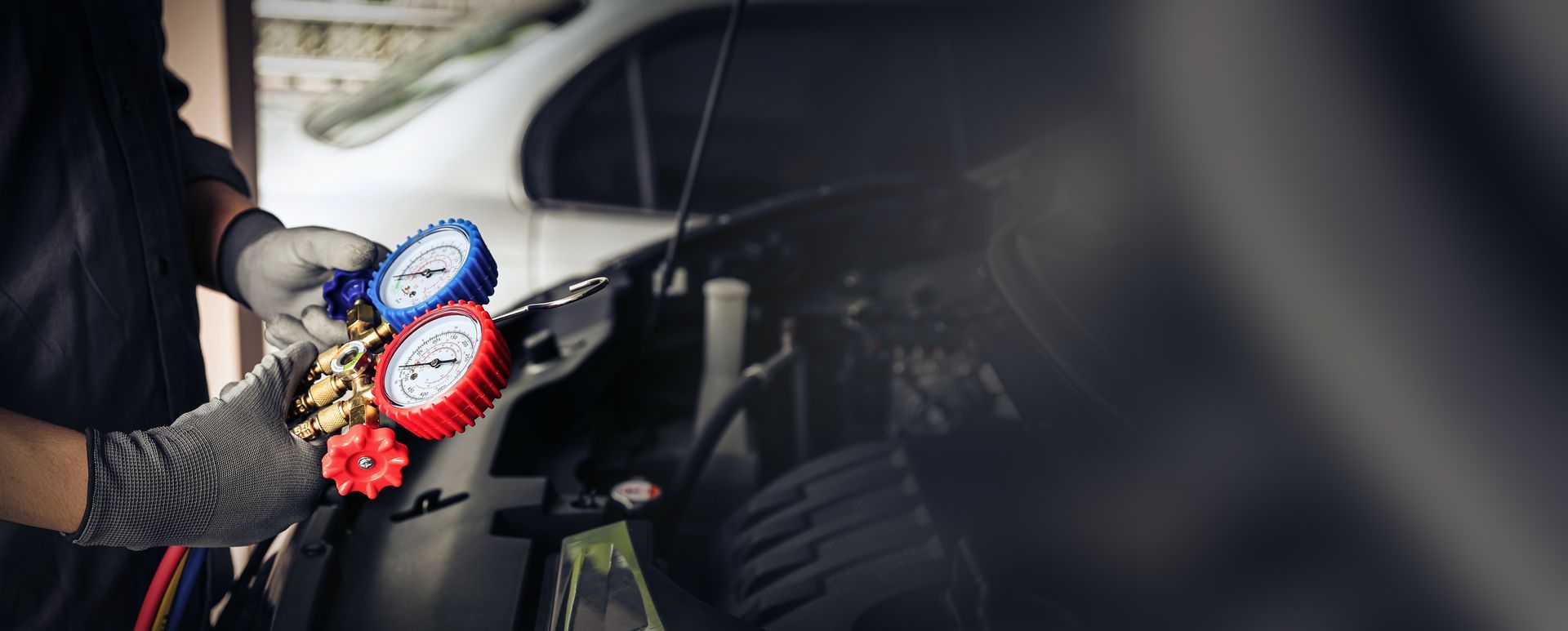 Person working on a car engine with a screwdriver.