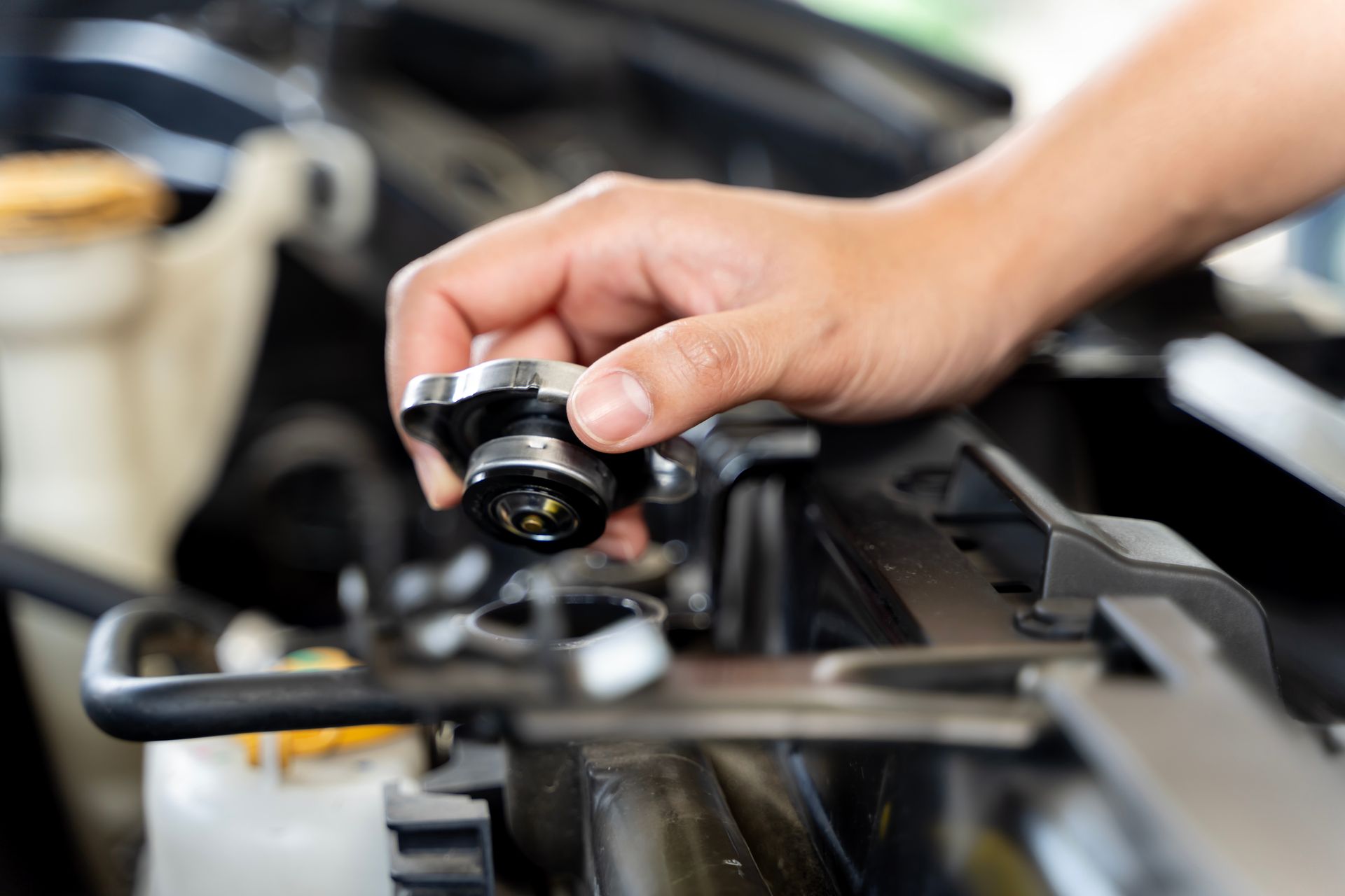 Hands installing a red car battery in an engine compartment.