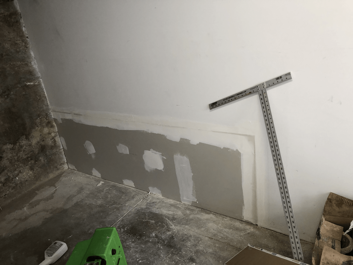 A room with a wall and a ruler on the floor.