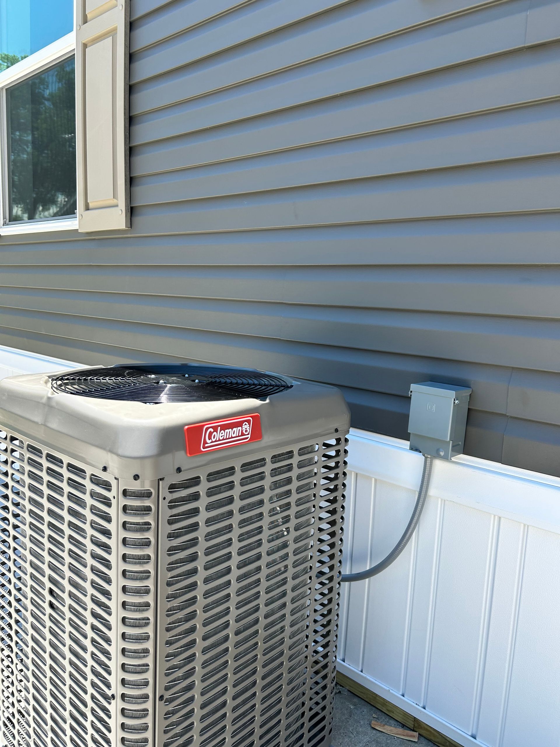 Outdoor air conditioner unit beside a blue house wall and window
