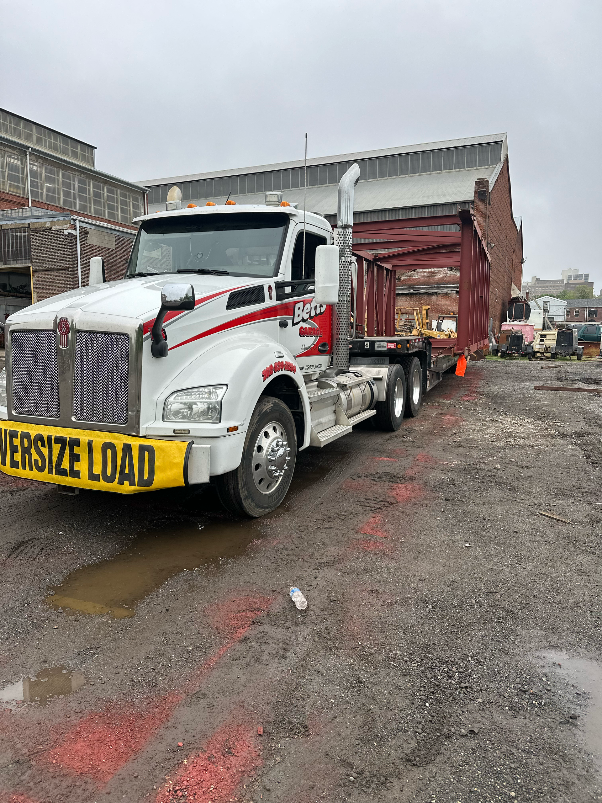 Betts Garage heavy-duty truck hauling equipment near industrial site