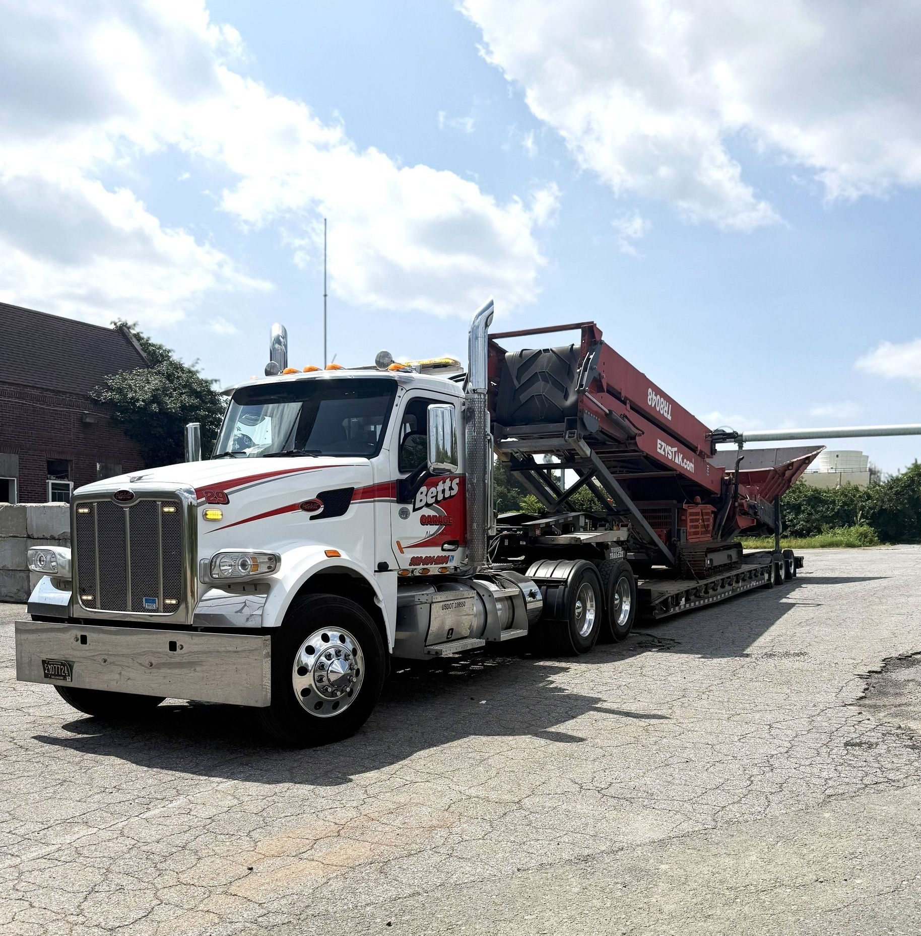 Betts Garage flatbed hauling large equipment at a worksite
