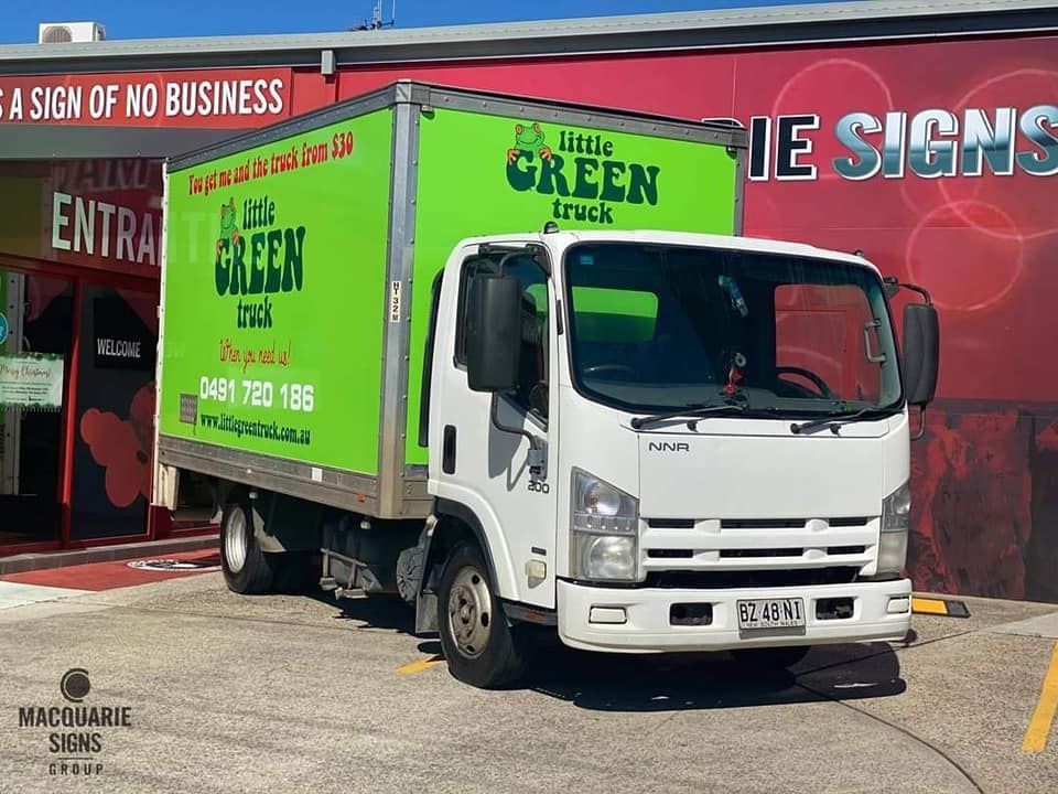 A man and a woman are carrying a cardboard box in a living room — Little Green Truck Port Macquarie in Wauchope, NSW
