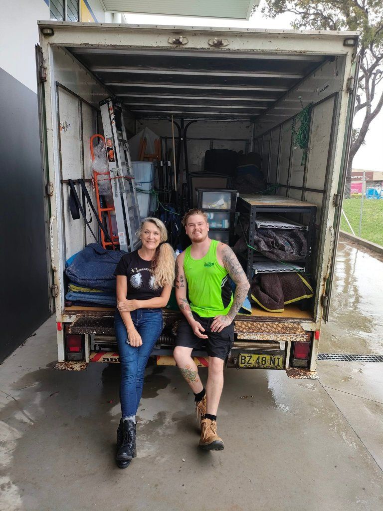 A Man and a Woman Are Sitting on the Back of a Moving Truck — Little Green Truck Port Macquarie in Wauchope, NSW