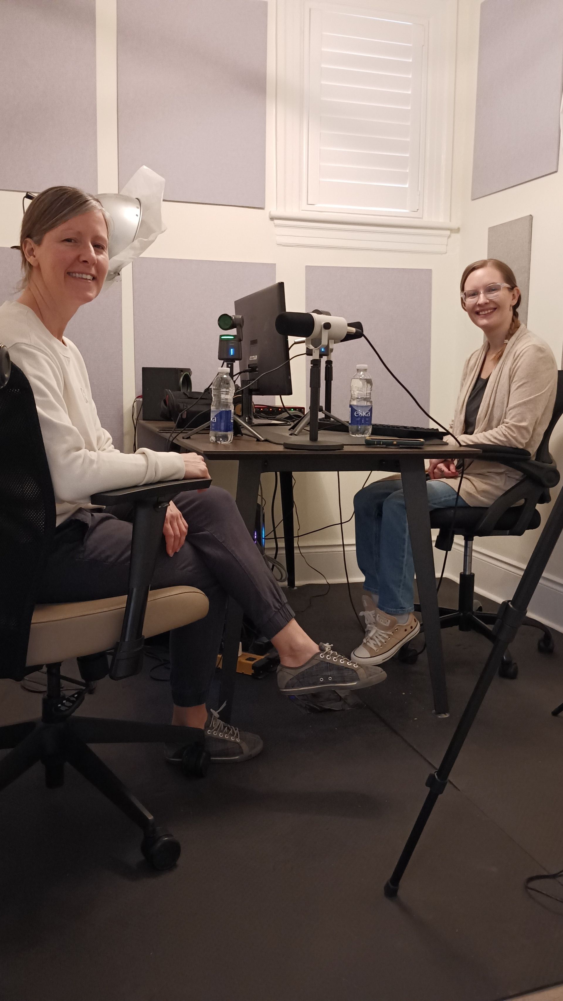 Two women are sitting at a desk in front of a computer.