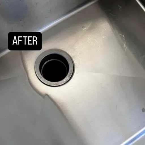 Clean, shiny stainless steel kitchen sink with a dark drain.