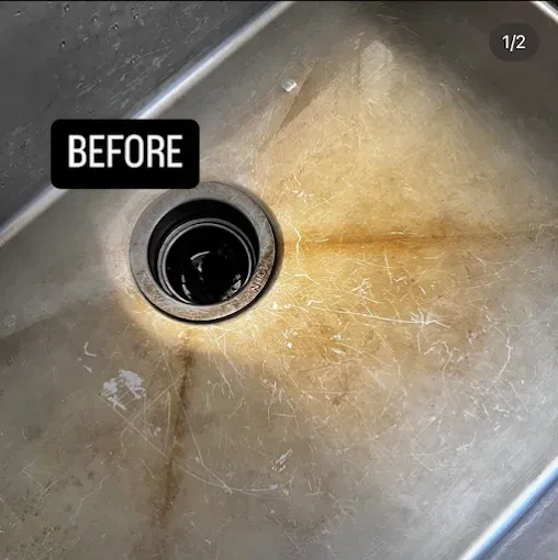 Stainless steel kitchen sink, stained and scratched with drain in the center, labeled 