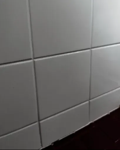 White tiled wall with dark grout lines, angled from the viewer's perspective.