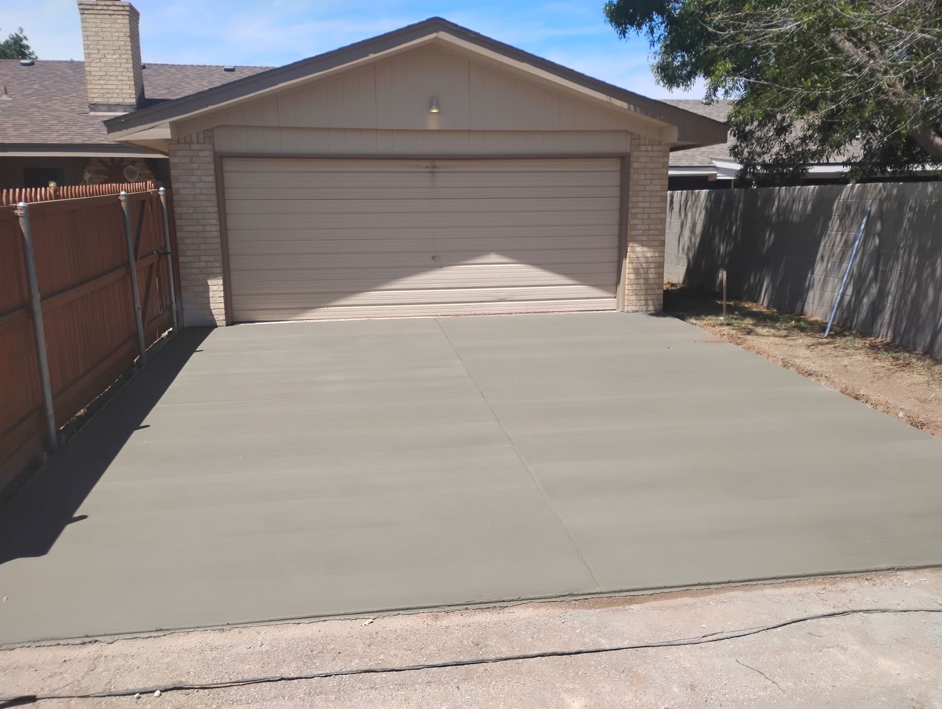 Residential driveway and two-car garage with a freshly paved concrete surface.