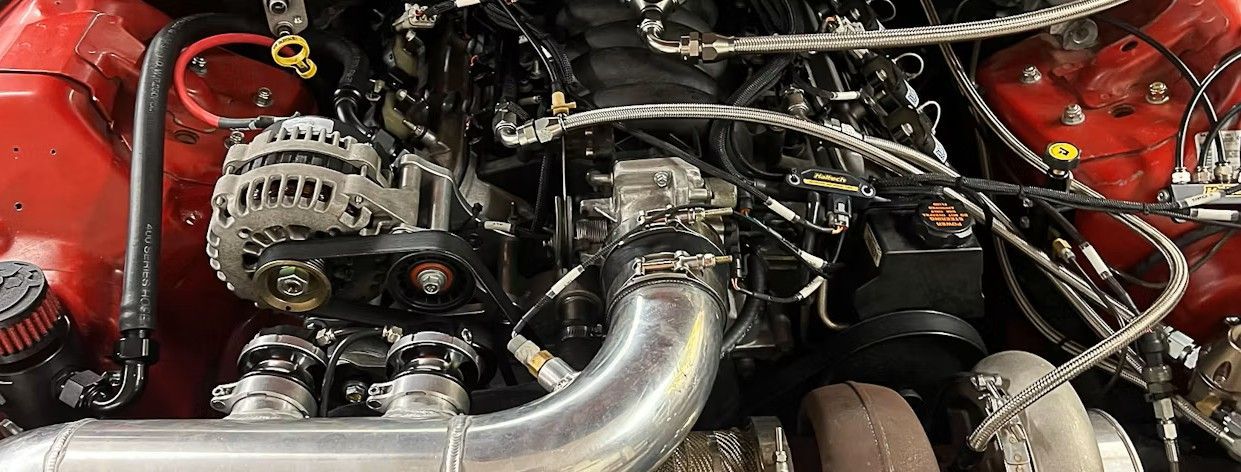 Engine bay with red accents and black components, including a turbocharger and alternator.