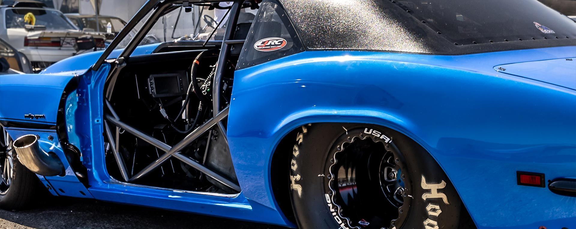 Blue race car with roll cage and black tires.