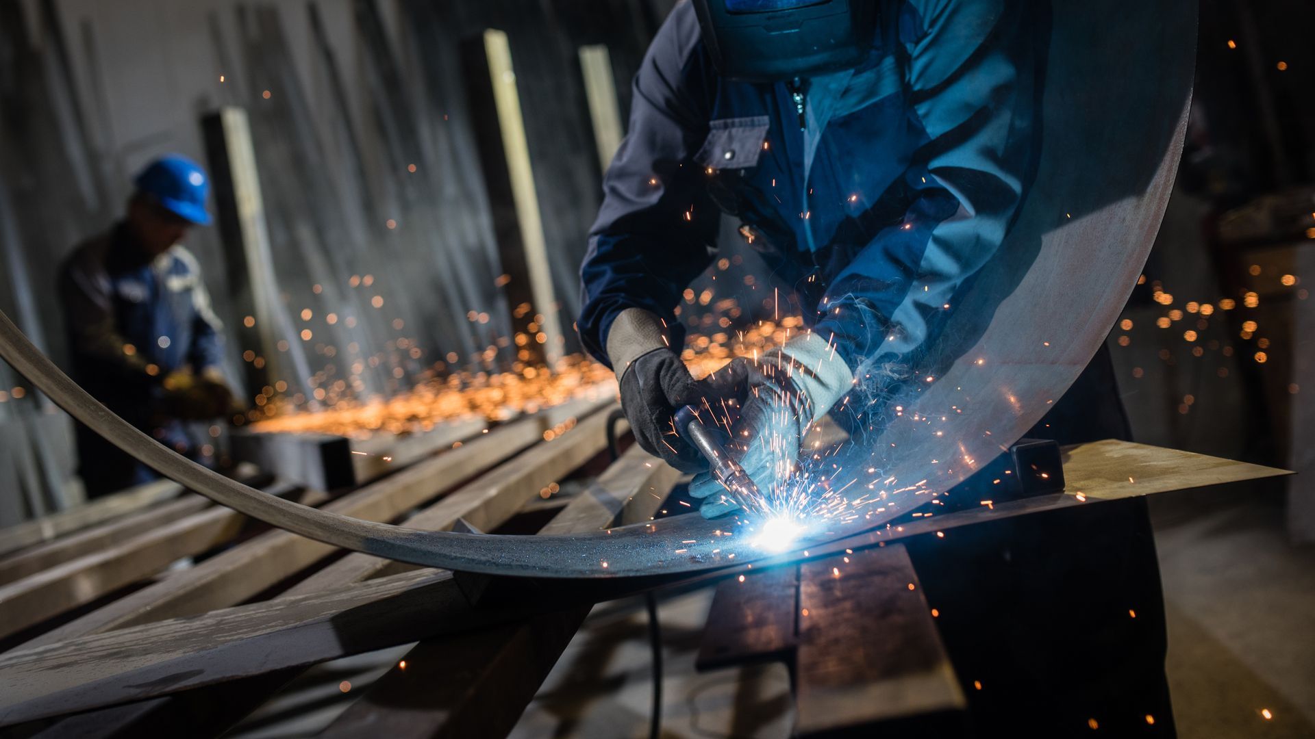 A man is welding a piece of metal in a factory.