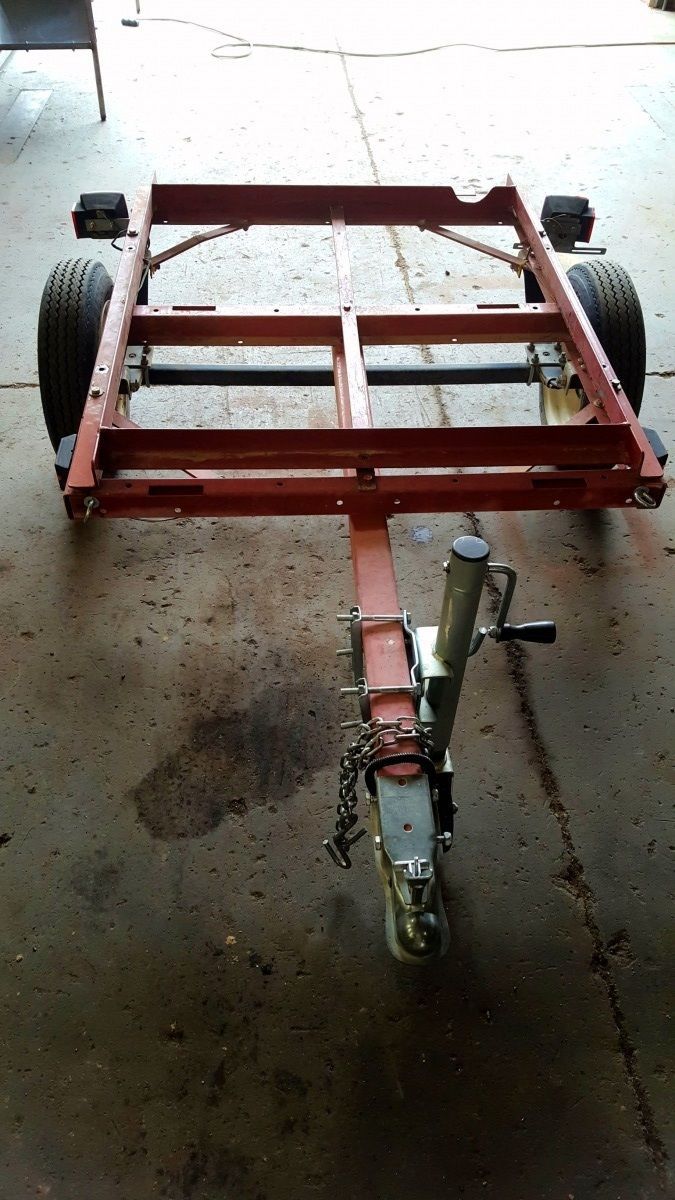 A red trailer is sitting on the ground in a garage.