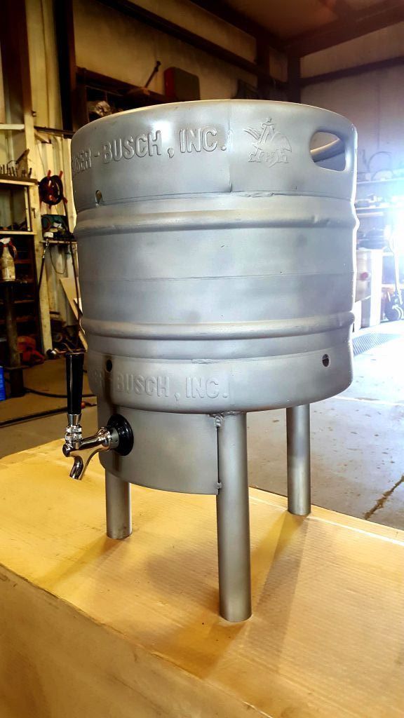 A stainless steel keg with a tap attached to it is sitting on top of a wooden table.