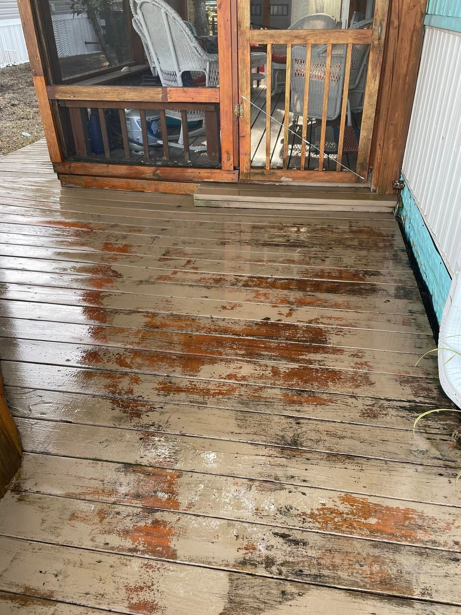 Rain-soaked wooden deck with scattered leaves leading to a screened porch door
