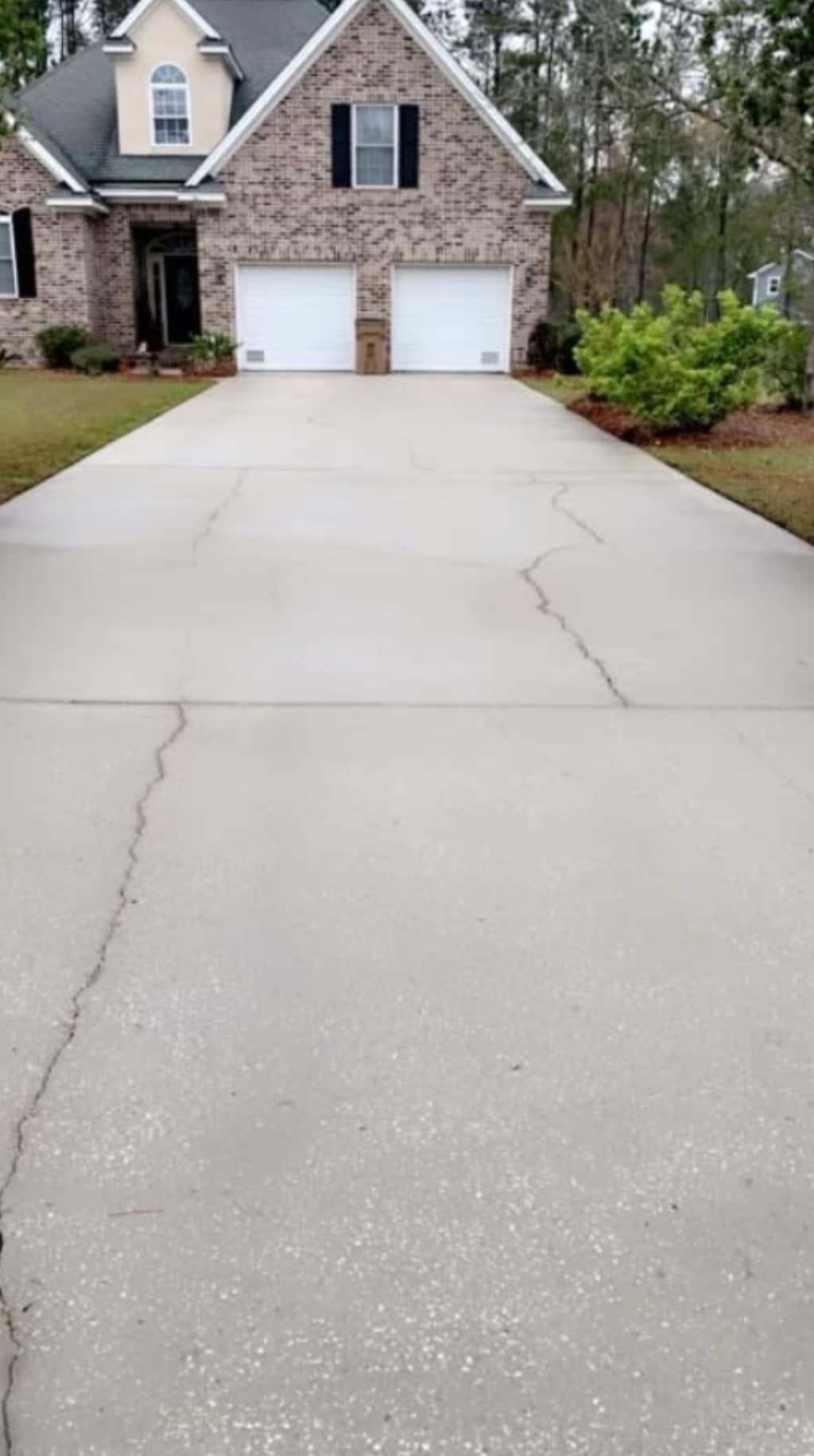 Suburban house with a wide concrete driveway and two white garage doors