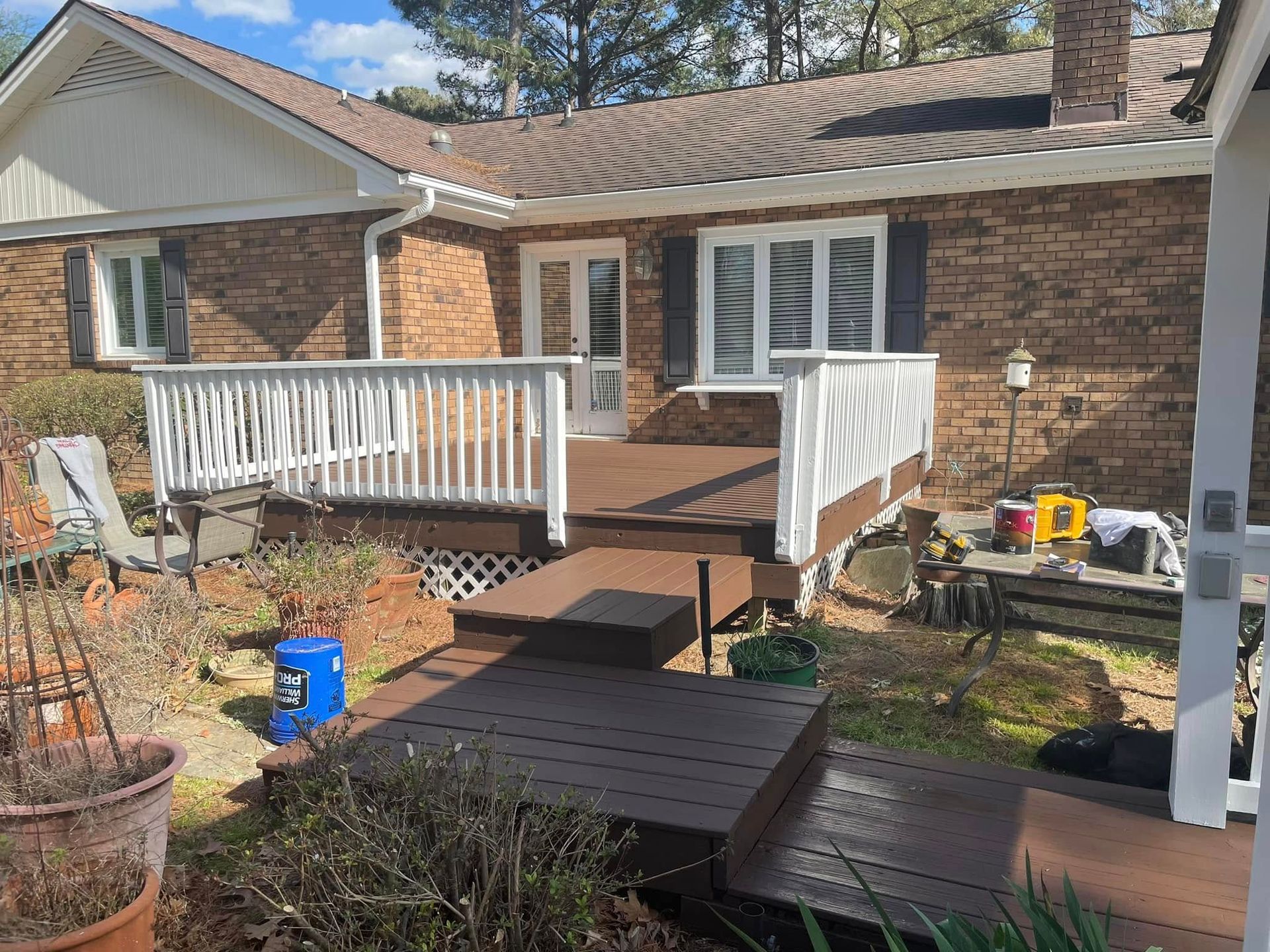 Brick house front porch with white railings and a wooden ramp in the yard