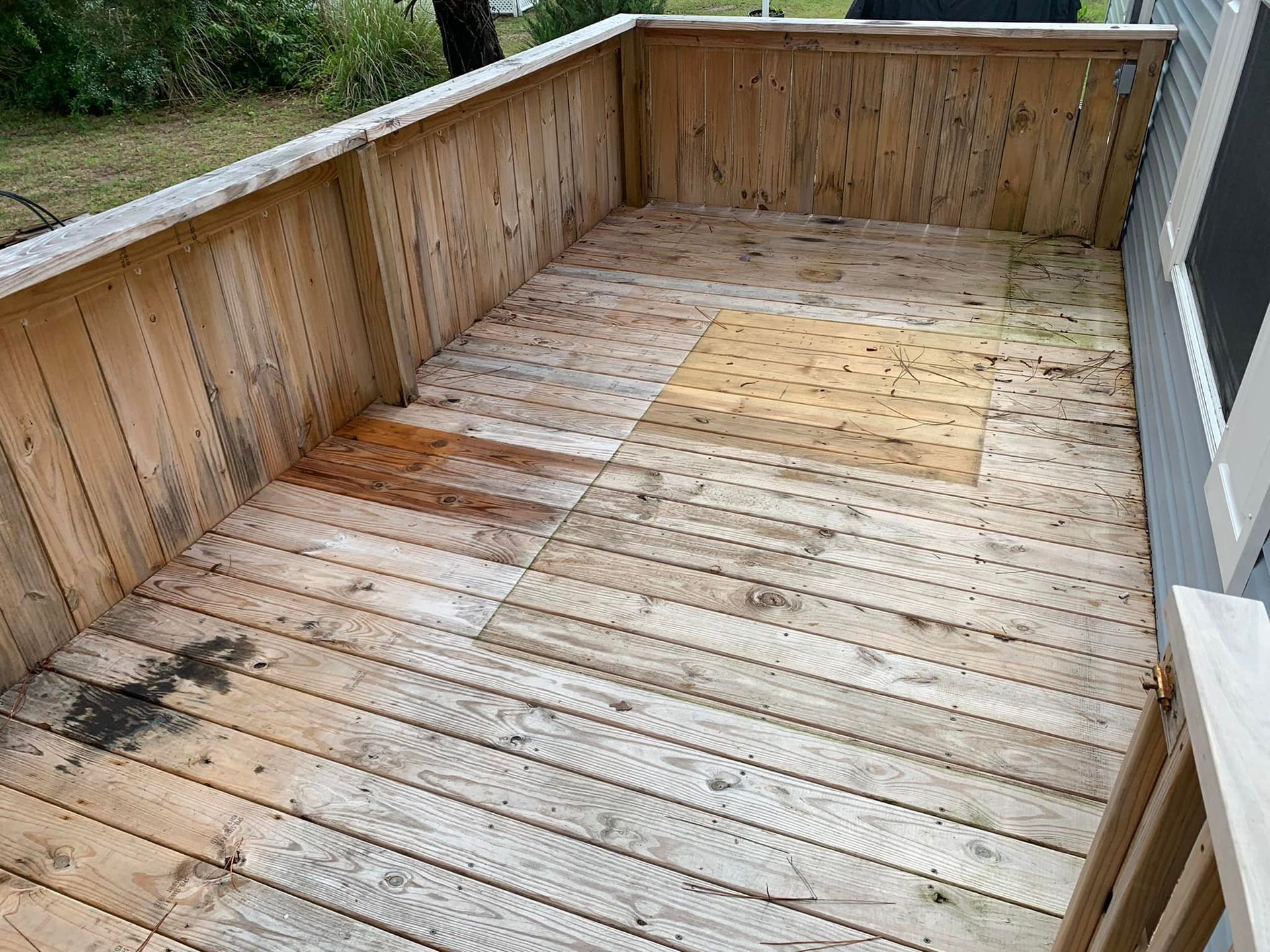 Wooden deck with weathered boards and a low railing, viewed from above.