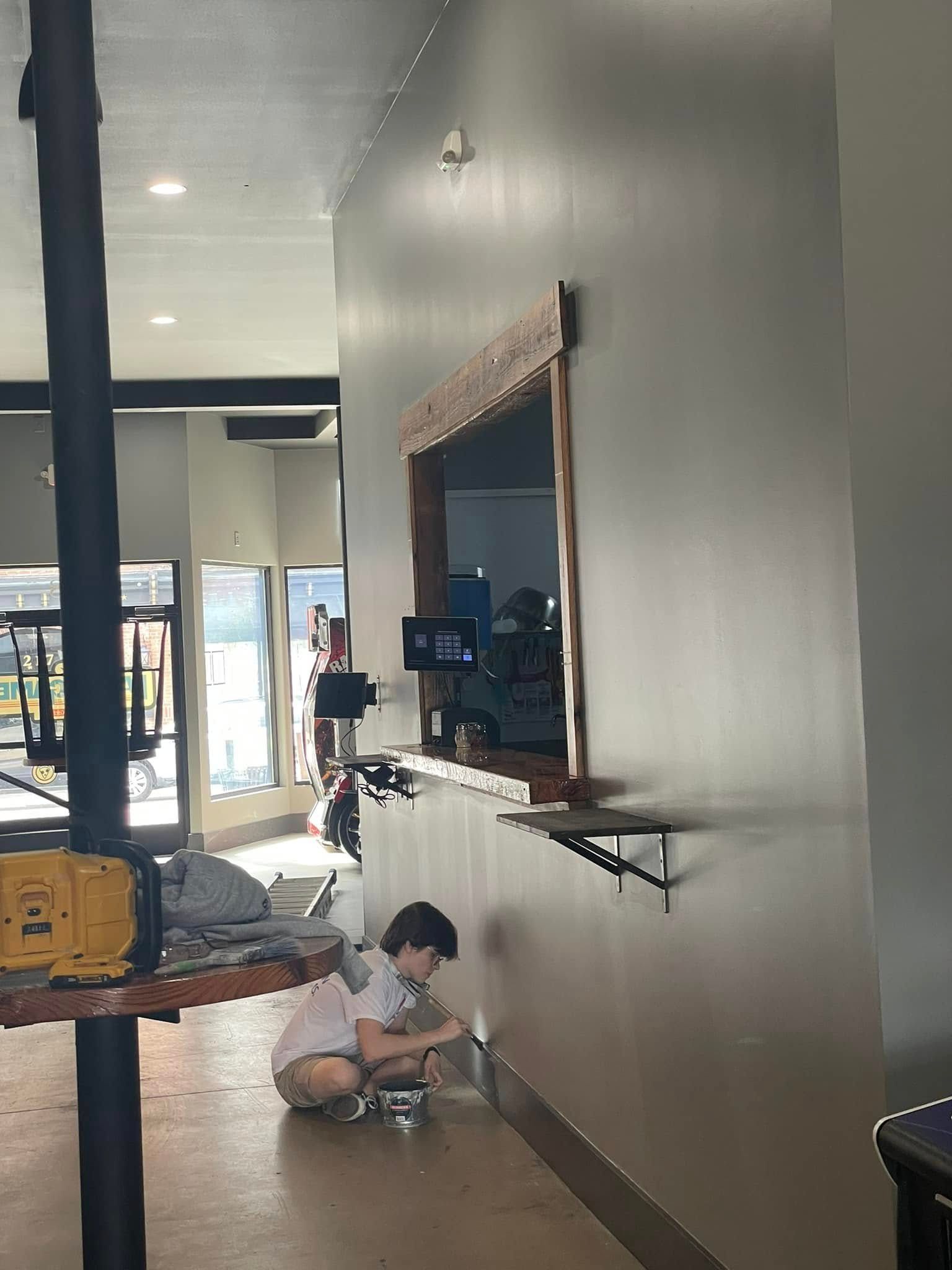 Child sitting on the floor in a hallway near a wall mirror and a small table