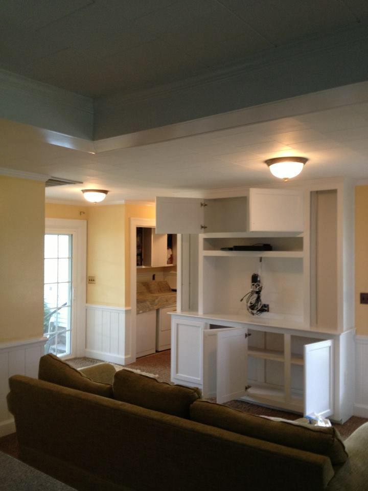 Living room with built-in white entertainment center and brown sofa under ceiling lights