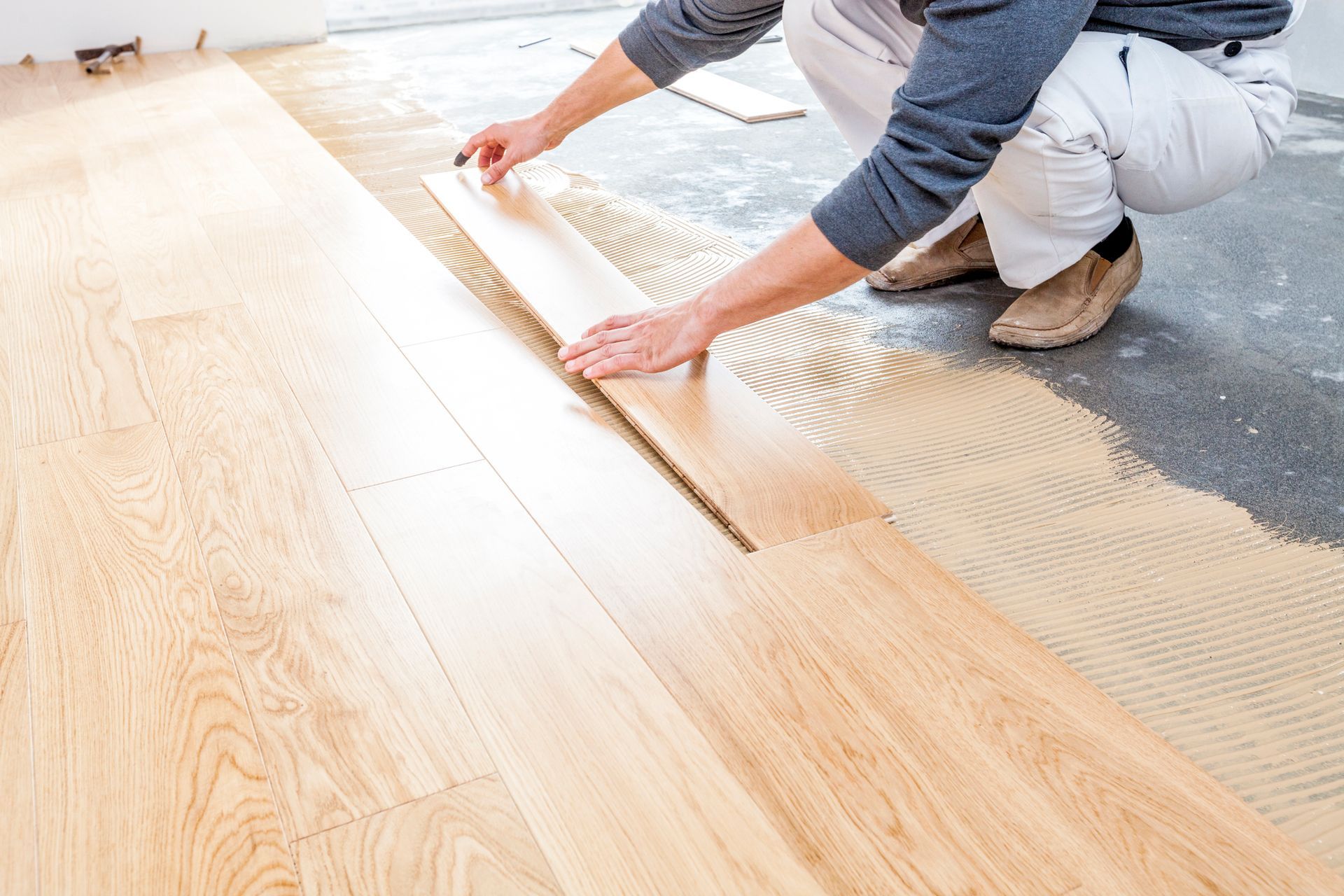 Un uomo sta installando un pavimento in legno in una stanza.