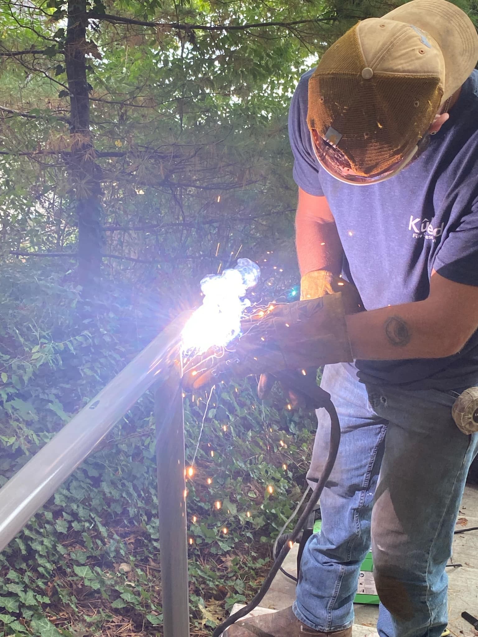 A person welding metal outdoors, bright sparks visible.