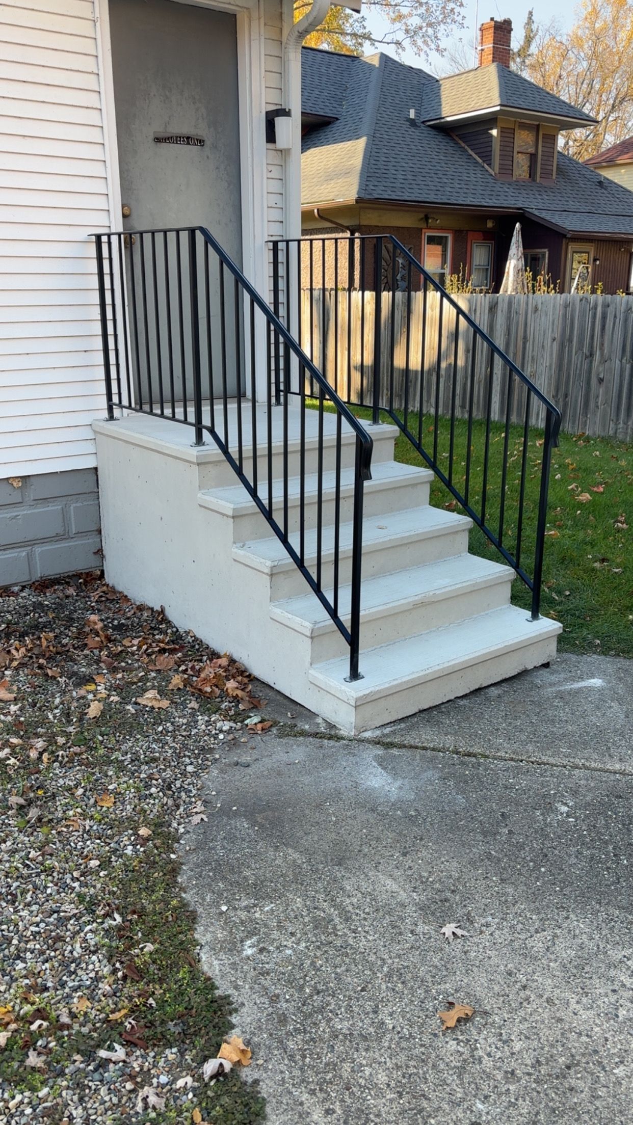 Concrete steps with black metal railing leading to a white building door.