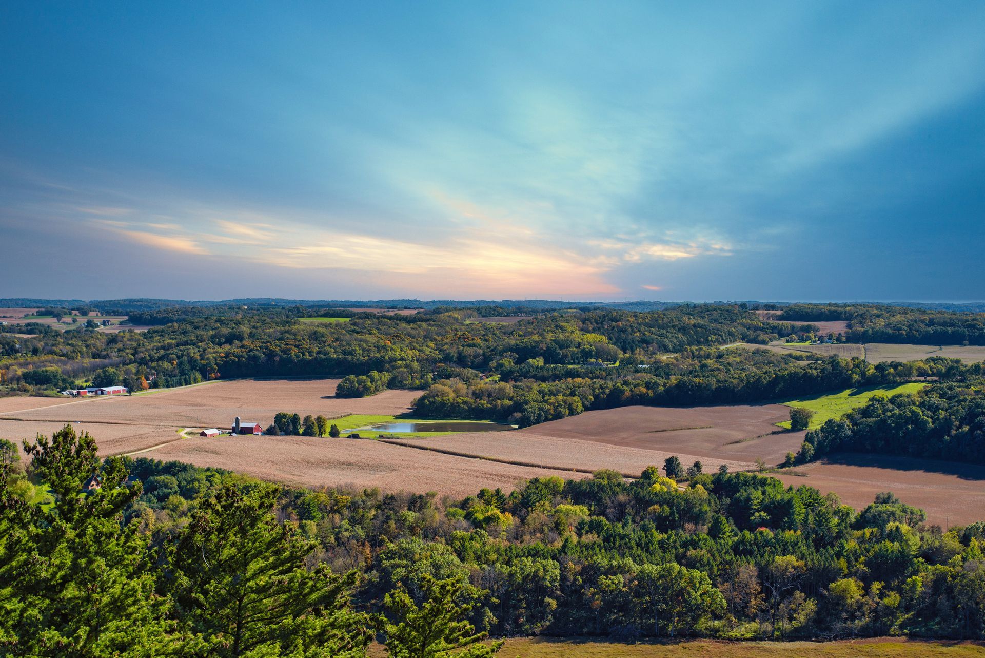 Overlook of agricultural landscape, fields and trees under a cloudy blue sky. Overlook of agricultural landscape, fields and trees under a cloudy blue sky.