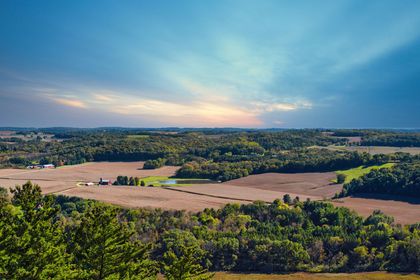 Overlook of agricultural landscape, fields and trees under a cloudy blue sky. Overlook of agricultural landscape, fields and trees under a cloudy blue sky.