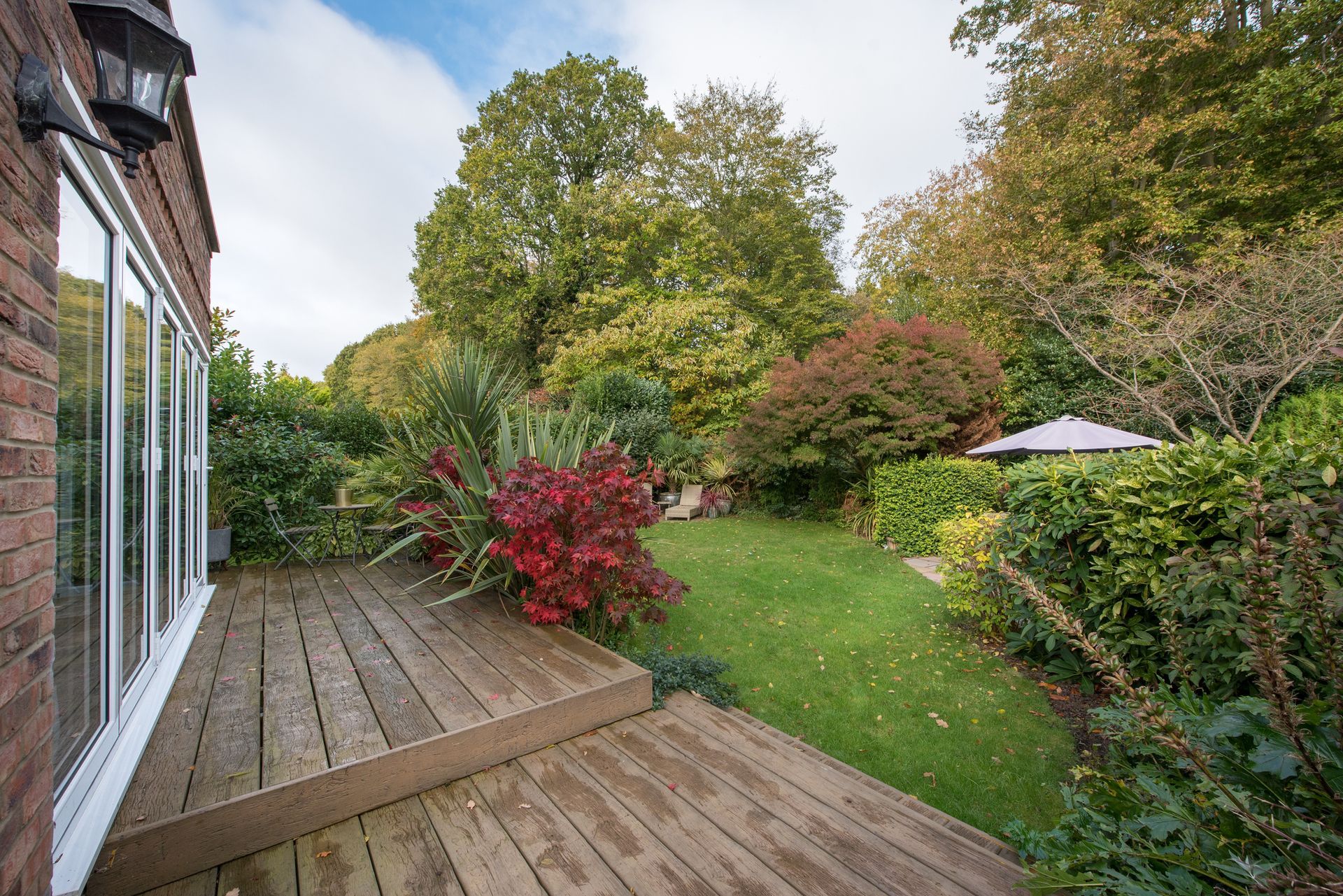 Three people in an unfinished room with large windows, looking up. A person points up. Wooden table with a hard hat.