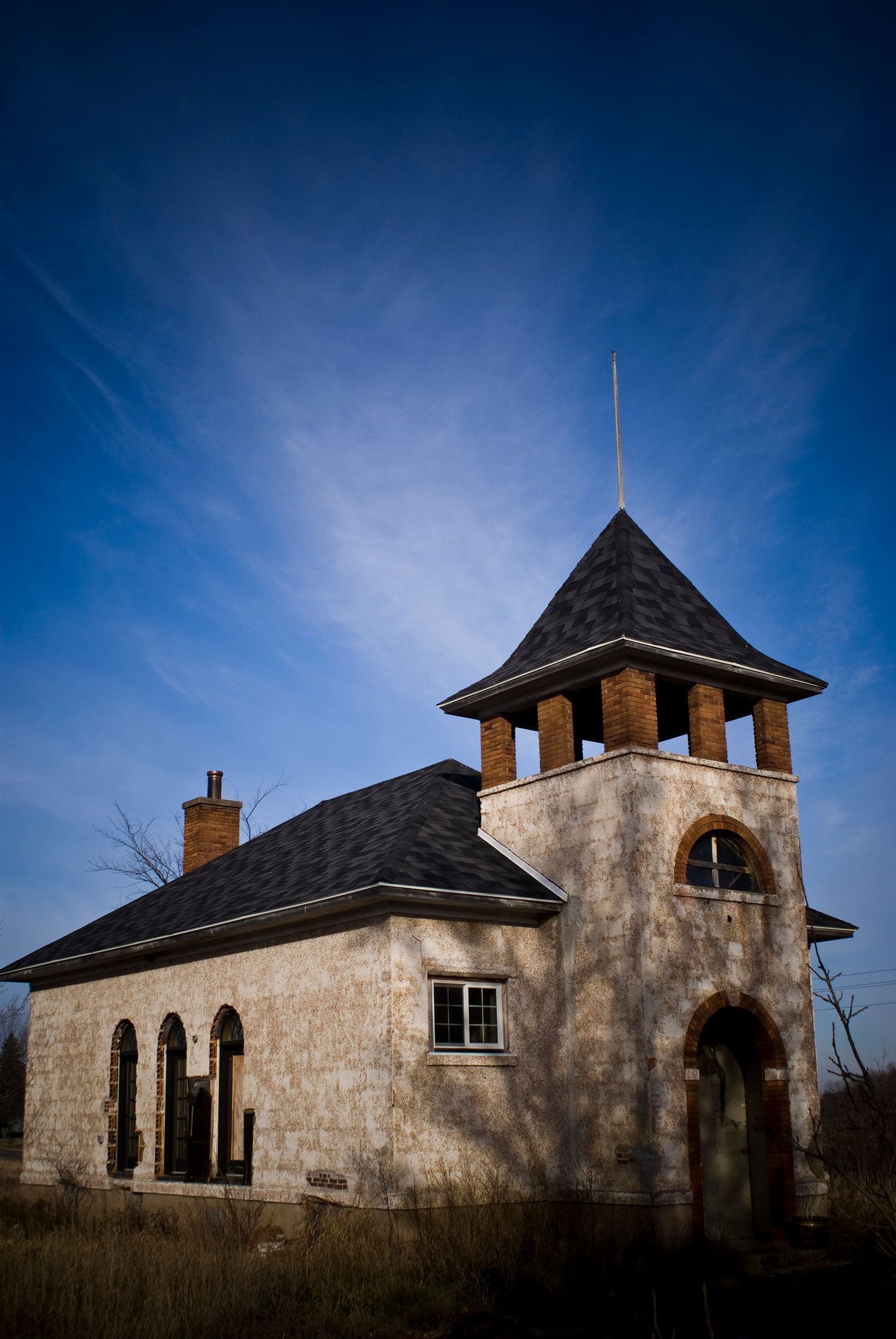 Old, weathered building with a tower under a bright blue sky. Old, weathered building with a tower under a bright blue sky.