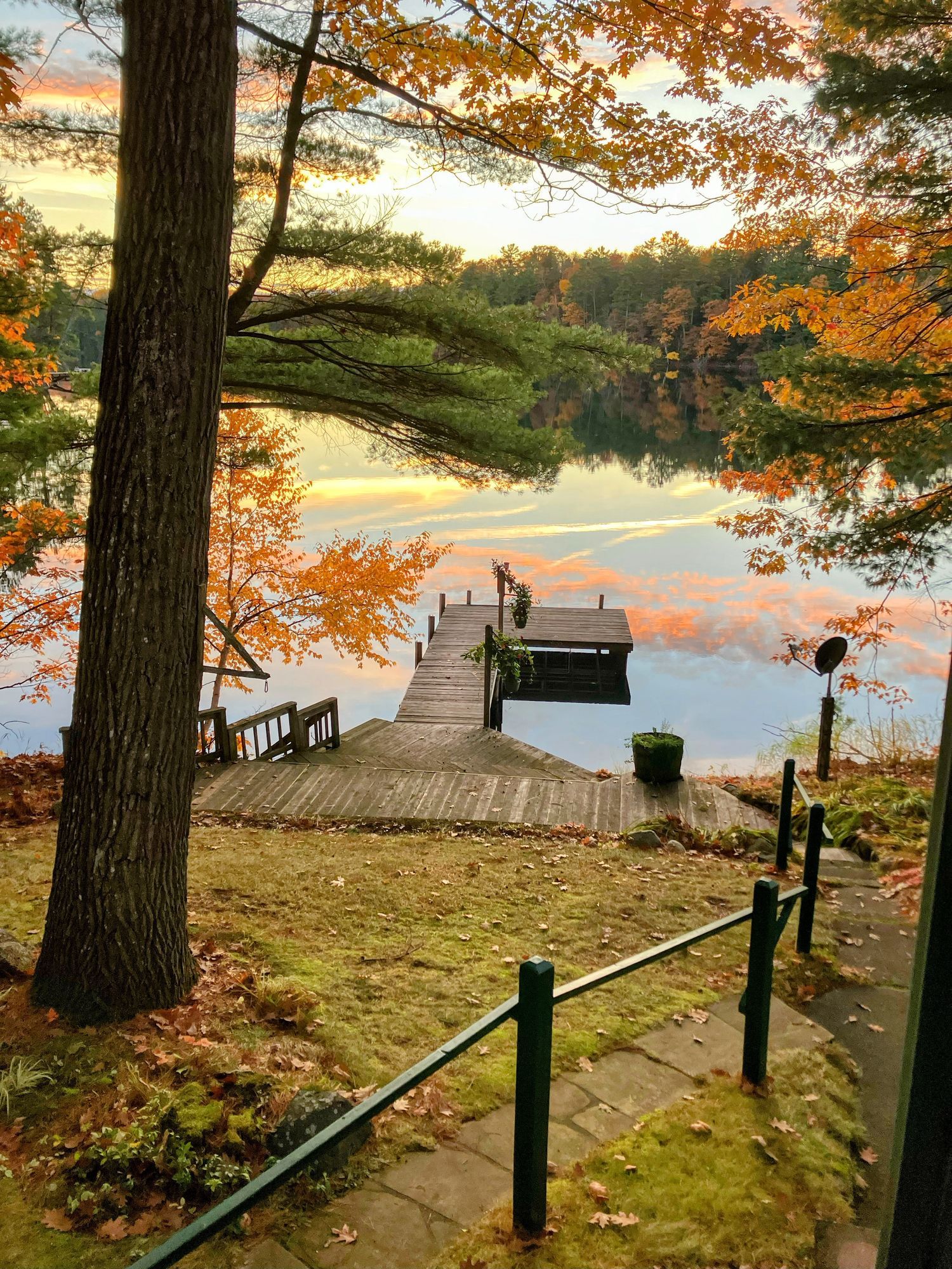 Wooden dock extending into calm lake, surrounded by autumn trees with orange and yellow leaves. Wooden dock extending into calm lake, surrounded by autumn trees with orange and yellow leaves.