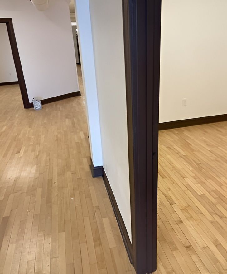 Empty, spacious room with hardwood floors and red columns; several tables and furniture are in the background.