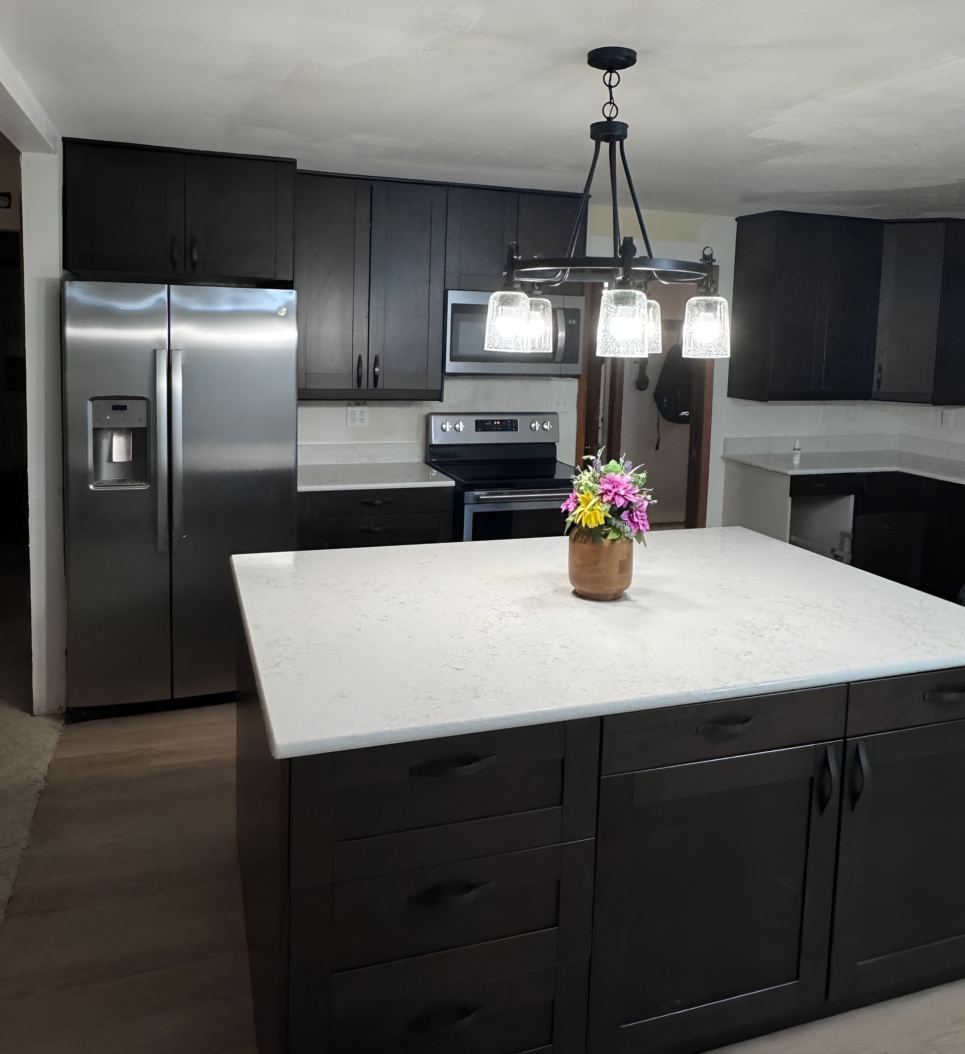 Modern kitchen with dark cabinetry, stainless steel appliances, and a white quartz island countertop. Modern kitchen with dark cabinetry, stainless steel appliances, and a white quartz island countertop.
