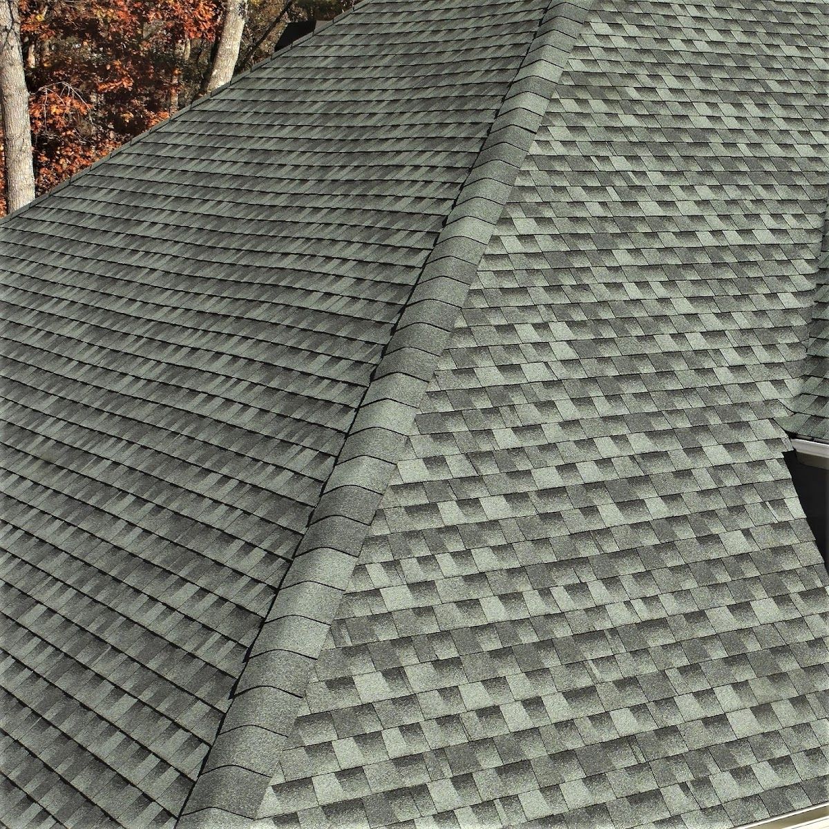 A close up of a gray roof with trees in the background.