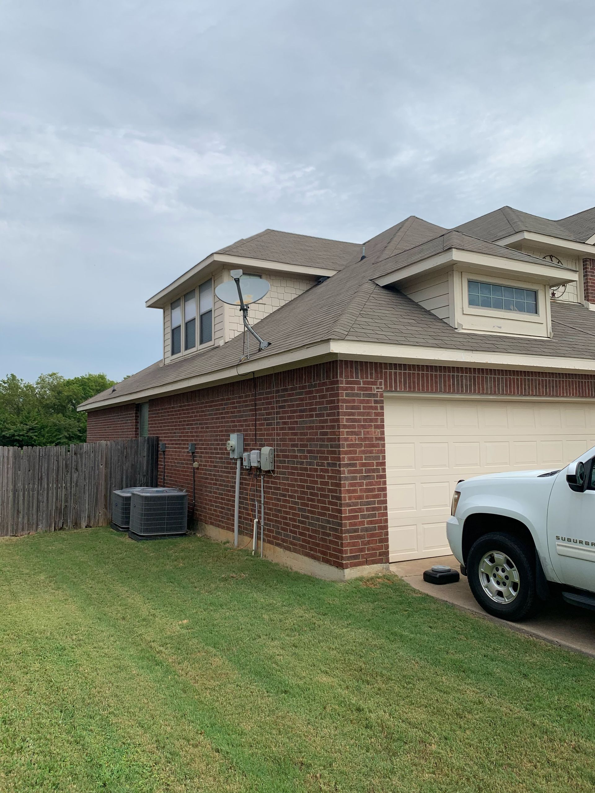 A white truck is parked in front of a brick house.
